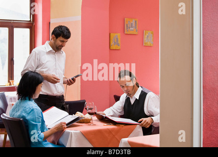 Cameriere prendendo gli ordini da parte dei clienti Foto Stock