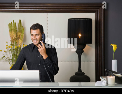 Receptionist maschio parlando al telefono Foto Stock