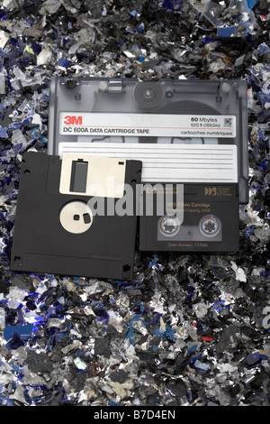 Pila di vecchio stile misto di supporti magnetici cartuccia nastro dat dds nastro e disco floppy su un letto di shredded supporti magnetici Foto Stock