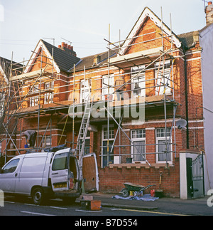 Costruttori con un camioncino bianco e ponteggi lavorando sul rinnovo a fronte di una bifamiliari casa di mattoni nel sud di Londra Inghilterra REGNO UNITO KATHY DEWITT Foto Stock