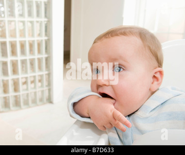 Un bambino seduto nella sua sedia alta. Foto Stock