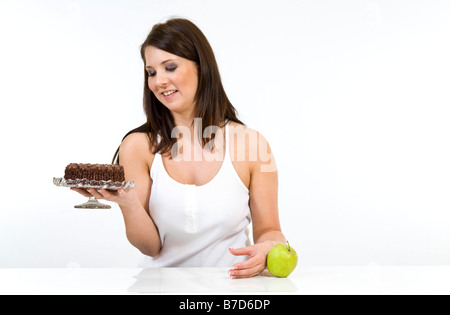 Attraente giovane donna di decidere tra un apple gateau al cioccolato. Foto Stock