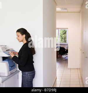 Lavoratore mediante copiatrice in ufficio occupato Foto Stock