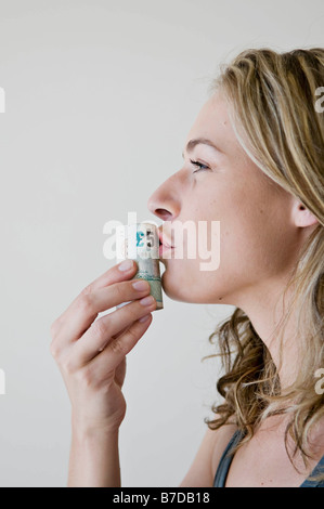 Una femmina di baciare un rotolo di denaro. Foto Stock