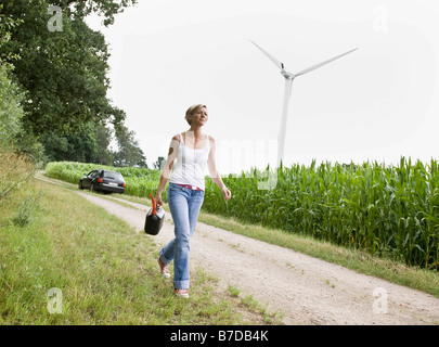 Donna che cammina con un gas può Foto Stock