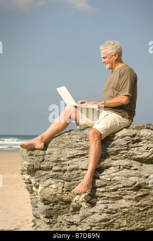 Maschio su una spiaggia utilizzando il computer Foto Stock