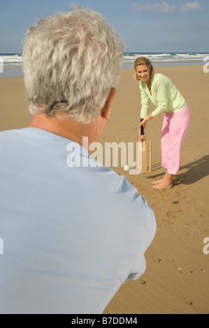 Giovane a giocare a cricket sulla spiaggia Foto Stock