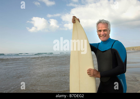 Maschio con tavola da surf su una spiaggia Foto Stock