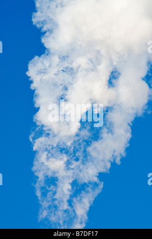 Il fumo bianco che scorre attraverso un cielo blu chiaro. Foto Stock