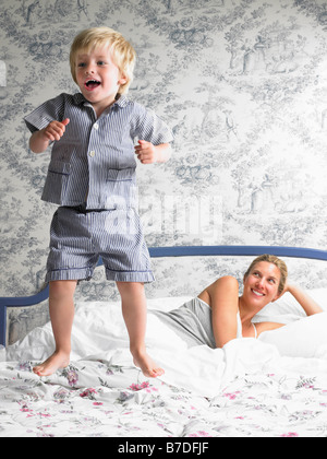 Ragazzo giocando con sua madre sul letto Foto Stock