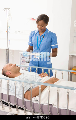 Un infermiere portando farmaco ad un paziente Foto Stock