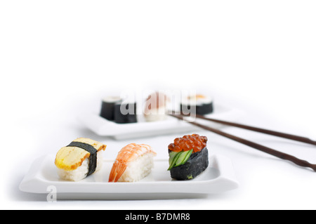 Diversi tipi di sushi posti di stile Giapponese piastre e bacchette isolati su sfondo bianco. Foto Stock