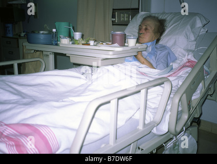 Un'anziana donna malati in ospedale in un letto in un reparto o una stanza Foto Stock