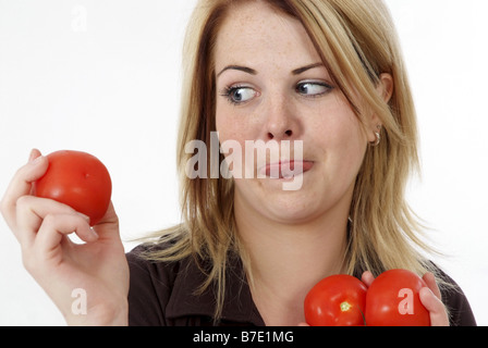 Donna con pomodori, leccare la sua braciole Foto Stock