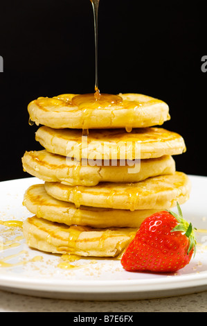 Il miele di versarla sulla pancake Foto Stock