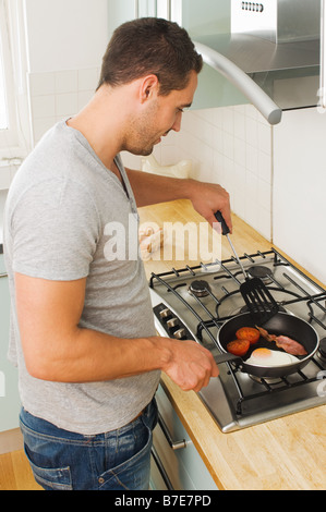 L'uomo la cottura colazione fritta Foto Stock