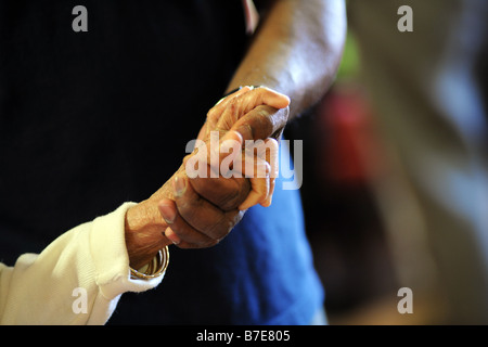 Una chiusura di anziane signore Sikh mani come Ella ha contribuito alla sua sedia in un contesto multiculturale la cura supplementare home Bradford West Yorkshire Foto Stock