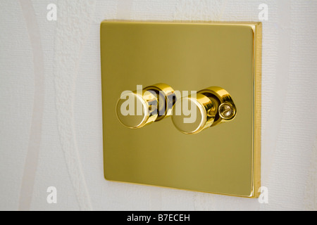 Metallo oro doppia reostato elettrico interruttore luce su una parete. Inghilterra Regno Unito Gran Bretagna Foto Stock