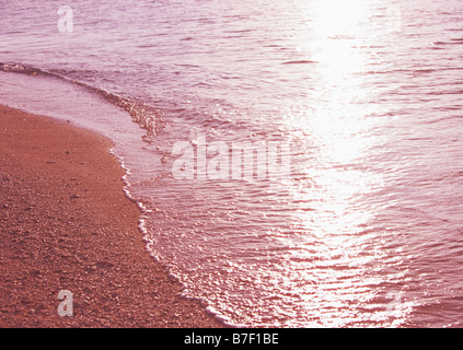 Per lappatura d'onda sulla battigia prima del tramonto Foto Stock