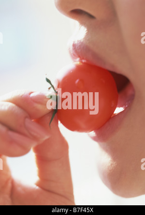 Donna di mangiare una ciliegia tomamo Foto Stock