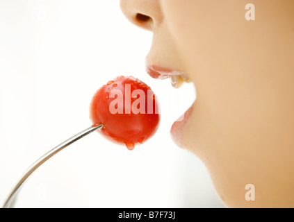 Donna di mangiare una ciliegia tomamo Foto Stock