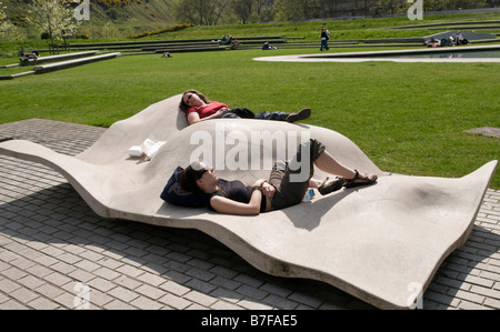 Due giovani donne a prendere il sole su una panchina di cemento in Holyrood Park Foto Stock