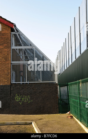 Case sul lato nazionalista di pace linea/parete in Belfast, con protezione di maglia di filo gabbia per fermare proiettili dall altro lato Foto Stock