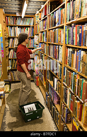 Navigazione donna seconda mano libri sugli scaffali in libreria Hay on Wye Regno Unito Foto Stock