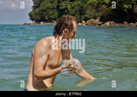 Uomo con i rifiuti raccolti dal mare durante una nuotata. Foto Stock