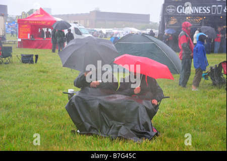 Seduta sotto la pioggia sotto gli ombrelloni Foto Stock
