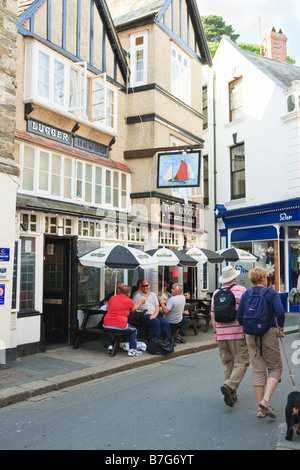 Il trabaccolo un pub di Fowey con bevitori seduto fuori e due passanti con il cane Foto Stock