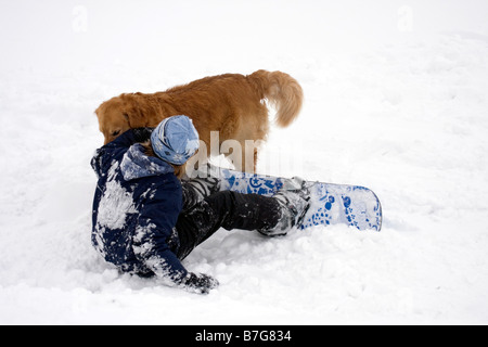 Teen boy e golden retriever avente il divertimento sulla neve. Foto Stock