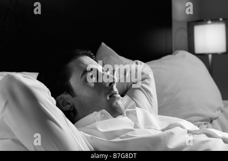 Giovane uomo solo nel letto Foto Stock