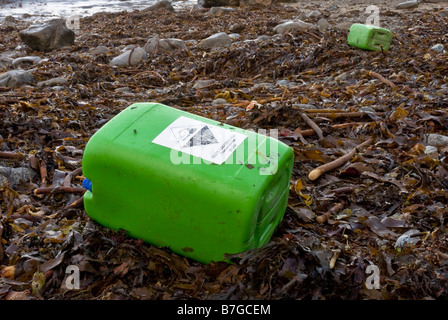 Contenitore chimici corrosivi con il simbolo di avvertimento lavato fino sulla coperta di alghe marine beach. Foto Stock