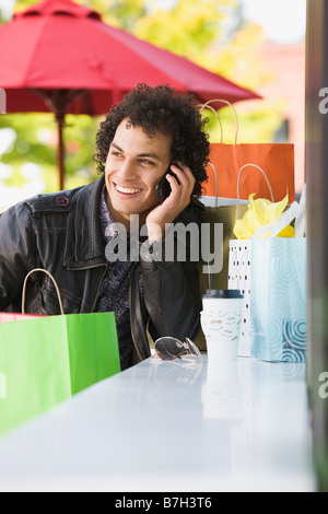 Medio Orientale con uomo shopping bags parlando al cellulare Foto Stock