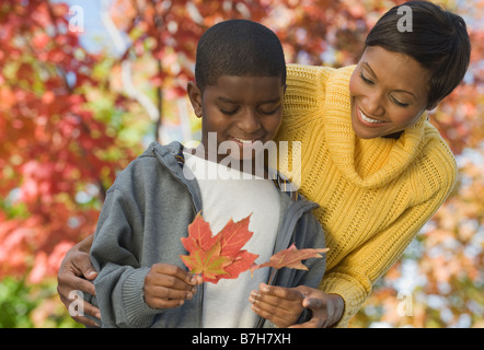 Madre africana e figlio guardando le foglie di autunno Foto Stock