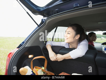 donna sorridente che apre il bagagliaio dell'auto mentre tiene la