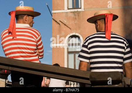 Due Venezia Italia gondolieri, indossando il tradizionale cappelli e magliette a strisce, prendere una pausa dal dare tours nei canali della città. Foto Stock