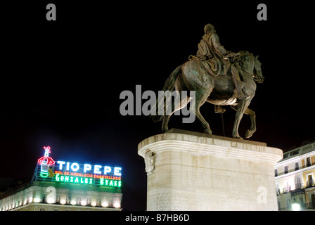 Tio Pepe insegna al neon e la statua equestre di re Carlos III. Vista notturna. Puerta del Sol. Madrid. Spagna. Foto Stock