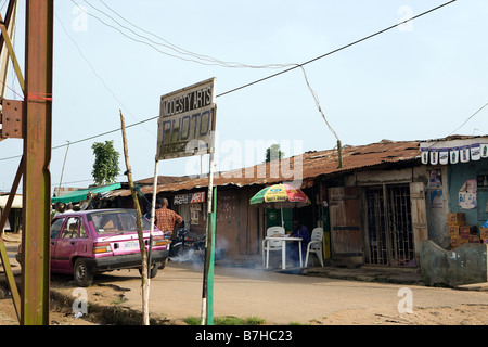 Un certo numero di persone stand in una strada di Epe, Nigeria, mentre un altro uomo si siede e fa sua la documentazione Foto Stock