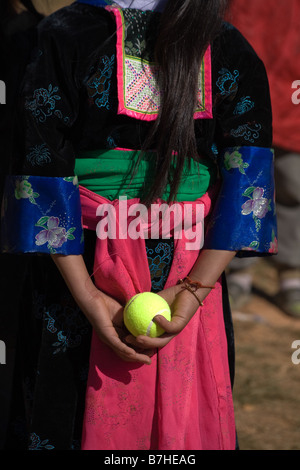 Una ragazza Hmong in costume tradizionale detiene una palla da tennis dietro la schiena per uso in Hmong Anno nuovo gioco di palla. Foto Stock