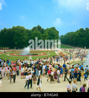 I turisti che visitano i giardini durante grandi acque giocare Chateau de Versailles Francia Foto Stock