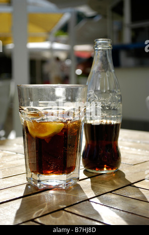 Bottiglia di coca cola con glas su un tavolo di legno Foto Stock