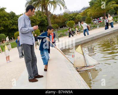 Un padre e figlio giocare con una barca nello stagno al Jardin du Luxembourg a Parigi, Francia Europa Foto Stock