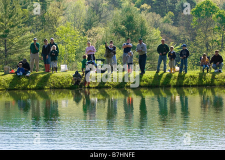 Le famiglie si sono riuniti intorno al laghetto per la stagione estiva la mattina pesca derby, riflessione Foto Stock
