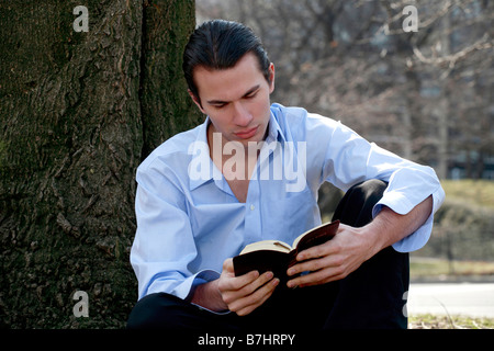 Uomo di leggere la sua Bibbia NIV a Central Park di New York. Foto Stock