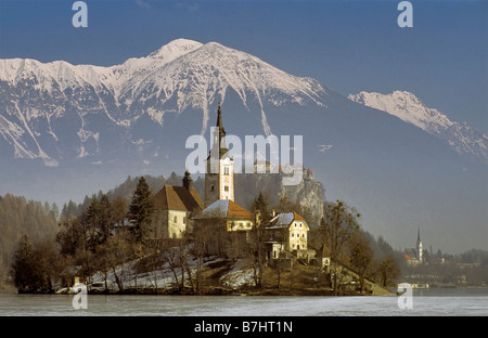 Chiesa sulla isola di Bled, il castello di Bled dietro e karavanke visibile in distanza, inverno, lago di Bled Slovenia Foto Stock