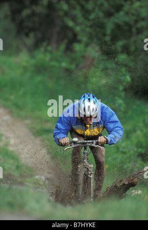 Giovane uomo mountain bike attraverso il fango vicino al Fernie, BC, Canada Foto Stock