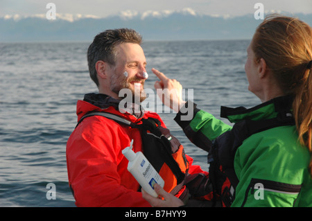 Man (30-35) e la donna (25-30) seduti in kayak di applicare la crema solare, Esquimalt, B.C. Foto Stock