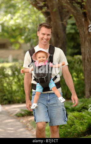 Uomo che cammina verso il basso street bambino portando in aiutano, Regina, Saskatchewan Foto Stock